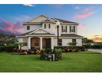 Inviting two-story home featuring manicured landscaping, warm exterior lighting, and a welcoming covered entryway at 17700 Sawgrass Run, Tavares, FL 32778