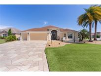 Charming single-story home with a well-manicured lawn and a beautiful, patterned driveway at 2077 Vickers Pl, The Villages, FL 32163