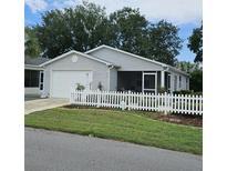 Charming single-story home featuring a white picket fence, attached garage, and well-manicured lawn at 2105 Escobar Ave, Lady Lake, FL 32159