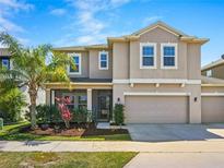Two-story home boasts an attached two-car garage, manicured landscaping, and a charming front porch at 395 Blue Cypress Dr, Groveland, FL 34736