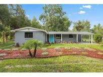 Charming home with a blue door and meticulously landscaped front yard featuring colorful plants and mulch at 4123 County Road 124, Wildwood, FL 34785