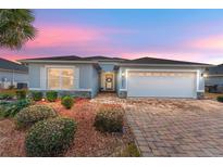 Charming single-story home featuring a brick driveway, two-car garage, and beautifully landscaped front yard at 4987 Belted Kingfisher Dr, Oxford, FL 34484