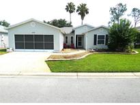 Charming single-story home with well-manicured lawn, gray siding and a screened garage door at 751 Old Oaks Ln, Leesburg, FL 34748