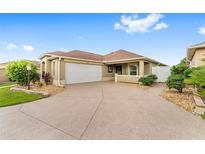Inviting home featuring a spacious driveway, well-manicured landscaping, and a charming covered entryway at 832 Parrish Pl, The Villages, FL 32163