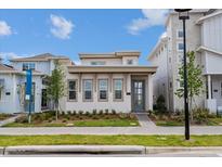Charming modern home featuring a stylish blue front door, complemented by manicured landscaping at 9674 Rodbell St, Orlando, FL 32827