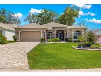 Inviting single-story home featuring a manicured lawn, paver driveway, and a well-maintained exterior at 1010 Sierra Blanca Ct, Lady Lake, FL 32159