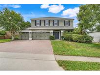 Charming two-story home with a three-car garage and beautiful landscaping, brick driveway, and a well-maintained lawn at 107 Wekiva Pointe Cir, Apopka, FL 32712
