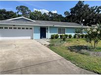 Charming single-story home with a blue exterior, attached garage, and well-maintained front lawn at 11812 Watts Ct, Tavares, FL 32778