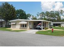 Charming single-story home with a carport and well-maintained landscaping under a sunny sky at 146 Hibiscus Way, Leesburg, FL 34748