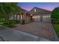 Charming single-Gathering home boasts an arched entryway and a two-car garage with a brick paver driveway at 15531 Waterleigh Cove Dr, Winter Garden, FL 34787