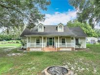 Charming home with a welcoming front porch, dormer windows, and a well-maintained lawn with mature shade trees at 17670 Se 283Rd Ave, Umatilla, FL 32784