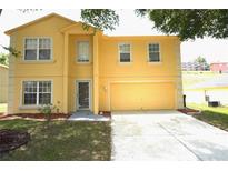 Two-story yellow home featuring an attached garage and well-maintained lawn at 2007 Country Brook Ave, Clermont, FL 34711