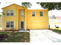 Two-story yellow home with an attached garage, well-maintained lawn and mature trees at 2007 Country Brook Ave, Clermont, FL 34711