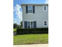 Two-story home featuring gray siding, dark shutters, manicured lawn and hedges at 212 Primrose Dr, Davenport, FL 33837