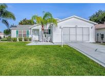 Charming single-story home with well-manicured lawn, white siding, and a decorative palm tree in the front yard at 2799 Privada Dr, The Villages, FL 32162