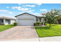 Charming one-story home featuring a brick-paved driveway and a well-manicured lawn at 29810 Anahid Dr, Leesburg, FL 34748