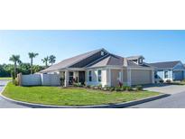 Charming single-story home with a well-manicured lawn, two-car garage and a welcoming front porch, set under a clear blue sky at 3466 Smedley Rd, The Villages, FL 32163