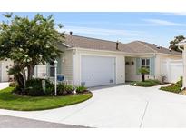 Charming home featuring a well-manicured lawn, attached garage, and inviting curb appeal at 579 Audrey Ln, The Villages, FL 32162