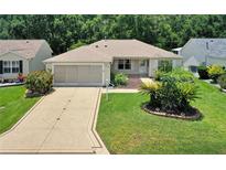 Charming single-story home featuring a well-manicured lawn and a beautifully patterned driveway at 8377 Se 177Th Bartram Loop, The Villages, FL 32162