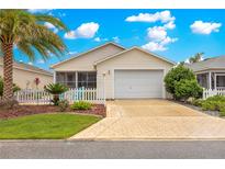 Charming single-story home with a well-manicured lawn, beautiful landscaping, and a white picket fence at 992 Davit Pl, The Villages, FL 32162