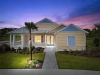 Charming single-story home with a welcoming porch and beautifully landscaped front yard at twilight at 1042 Sugarloaf Key Loop, Lady Lake, FL 32159