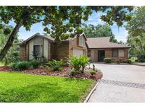 Charming brick home with well-manicured landscaping, green lawn, and a spacious driveway at 112 Waterwood Dr, Yalaha, FL 34797