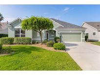 Charming single-story home featuring a well-manicured lawn, mature landscaping, and a two-car garage at 1122 Magrath Way, The Villages, FL 32162