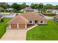 Charming single-story home featuring a two-car garage, manicured lawn, and lovely landscaping at 1414 Cove Pl, Tavares, FL 32778