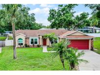 Charming single-story home featuring a lush lawn, palm trees, and a red garage door at 15916 Indian Wells Ct, Clermont, FL 34711