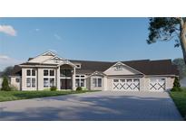 An elegant home features a spacious driveway, large windows, and a three-car garage with unique cross beam garage doors at 2421 Shady Ln, Groveland, FL 34736