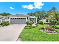Charming home with a lush, landscaped front yard and screened two-car garage at 27302 Stoney Brook Dr, Leesburg, FL 34748
