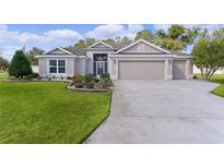 Charming single-story home with a well-manicured lawn, colorful flowerbeds, and a three car garage at 2954 Heiny Pl, The Villages, FL 32163