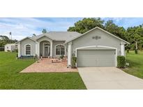 Charming single-story home with a well-manicured lawn and a brick-paved seating area at 316 Dupont Cir, Howey In The Hills, FL 34737