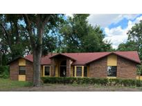 Charming single-story home with brick facade, red roof, and manicured front yard landscaping at 37236 Cherry Lake Rd, Fruitland Park, FL 34731