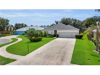 Well-maintained home featuring a lush green lawn, manicured landscaping and a concrete driveway leading to a three-car garage at 3819 Saint Emma Ct, Leesburg, FL 34748