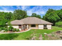 Charming single-story home with well-maintained lawn and walkway surrounded by lush trees and beautiful landscaping at 39132 Grays Airport Rd, Lady Lake, FL 32159