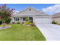 Charming single-story home with a well-manicured lawn, flower beds, and an attached two-car garage at 3978 Nottingham Loop, The Villages, FL 32163