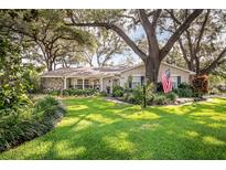 Charming single-story home featuring a well-manicured lawn, mature trees, and a welcoming American flag at 500 Lake Forest Cir, Mount Dora, FL 32757