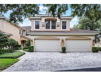 Charming two-story home with a red tile roof and a three car garage on a brick driveway at 52 Camino Real Blvd, Howey In The Hills, FL 34737