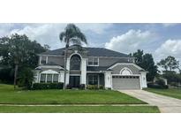 Charming two-story home with attached garage and well-manicured front lawn and mature palm tree at 633 Grand Cypress Pt, Sanford, FL 32771