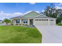 Beautiful single-story home featuring a three-car garage and a well-manicured lawn with flowerbeds at 6991 Sugar Creek Path, The Villages, FL 34762
