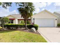 Inviting single-story home with manicured landscaping, a two-car garage, and a charming front yard at 891 Lucky Ln, The Villages, FL 32162