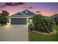 Charming single-story home featuring a well-manicured lawn, a two-car garage, and a beautifully landscaped yard at dusk at 2448 Bachman Path, The Villages, FL 32162