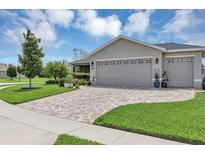 Charming home featuring a well-manicured lawn, paver driveway, and a neutral-colored exterior at 26601 Otter Creek Ln, Leesburg, FL 34748