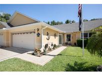 Charming home exterior with a two-car garage, well-maintained lawn, and nautical decorations at 26917 White Plains Way, Leesburg, FL 34748