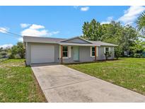 Charming single-story home with a light gray exterior, a well-maintained lawn, and a paved driveway at 4 Kristin Ln, Eustis, FL 32726