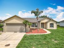 Charming single-story home featuring a well-manicured lawn, mature palm trees, and an attached two-car garage at 439 Gentle Breeze Dr, Minneola, FL 34715