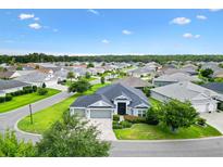 Stunning aerial view of a well-maintained home with lush landscaping and a three-car garage in a desirable community at 5868 Wood Stork Way, The Villages, FL 32163