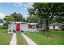 Charming single story home with red door and shutters, and a well-maintained lawn at 780 N Kentucky Ave, Umatilla, FL 32784