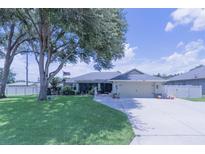 Charming single-story home featuring well-manicured lawn, mature trees, and attached two-car garage at 8489 Se 158Th Pl, Summerfield, FL 34491